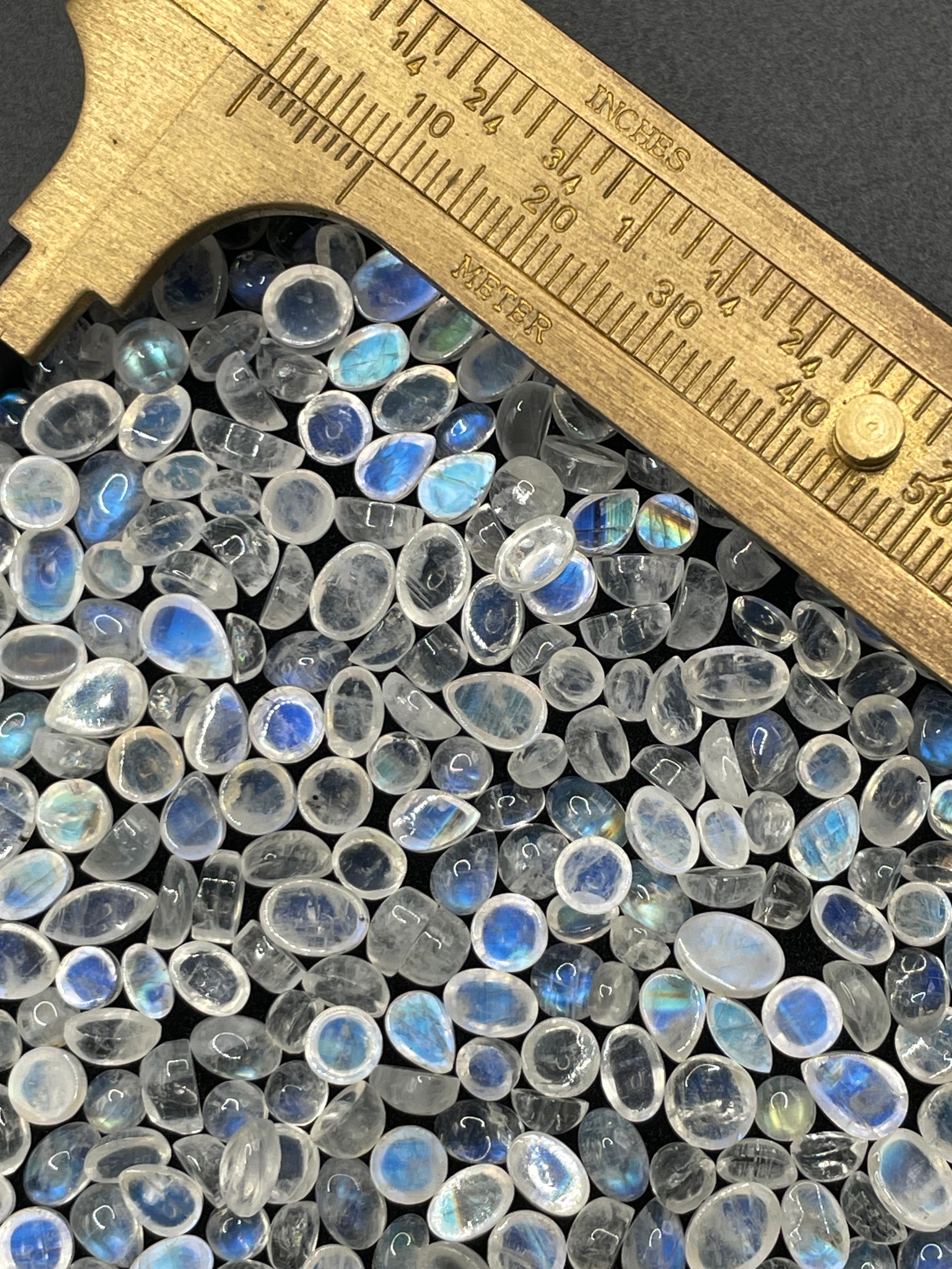 Box of random assorted natural Rainbow Moonstone crystal cabochon gemstones stones with measuring ruler